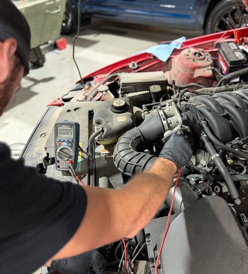Nick Tizzano testing a circuit with a multimeter during diagnostics at Tizzano Automotive