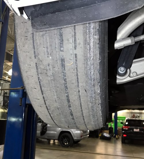 tire worn unevenly across the tread, inspected on the lift at Tizzano Automotive in Plain City, OH